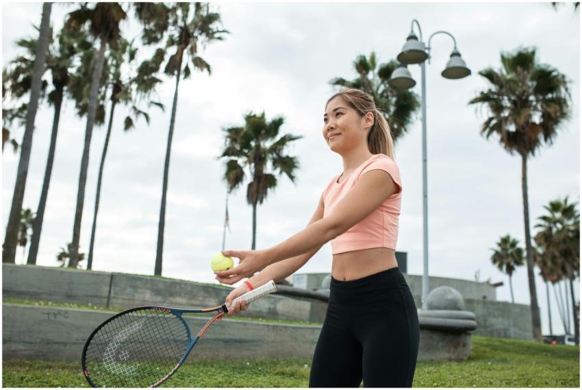 Asian woman preparing to serve during tennis game