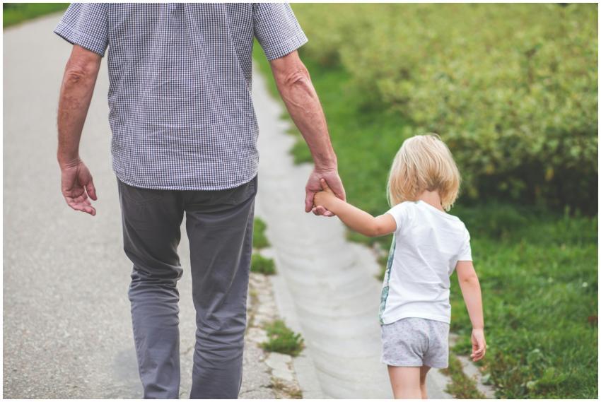 A grandparent holds hands with a child, walking on