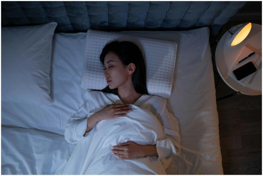 Calm and peaceful woman resting in bed under dim l