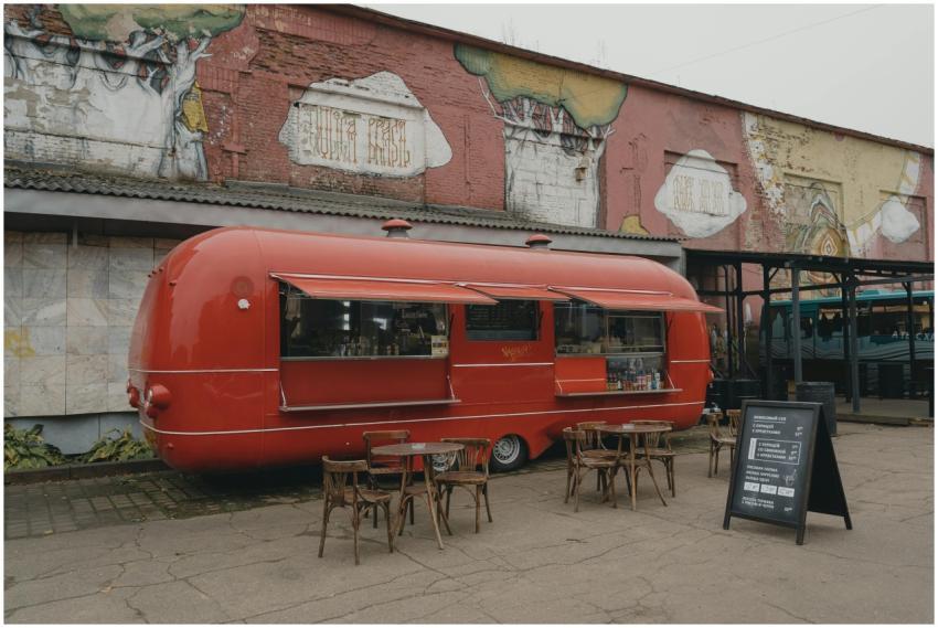 Red food truck with outdoor seating against mural-