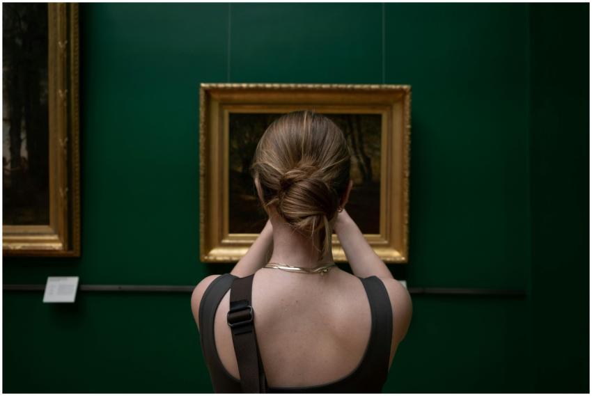Back view of a woman photographing a painting in a