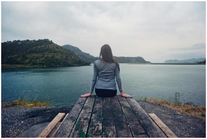 A woman sitting on wooden planks, enjoying a seren