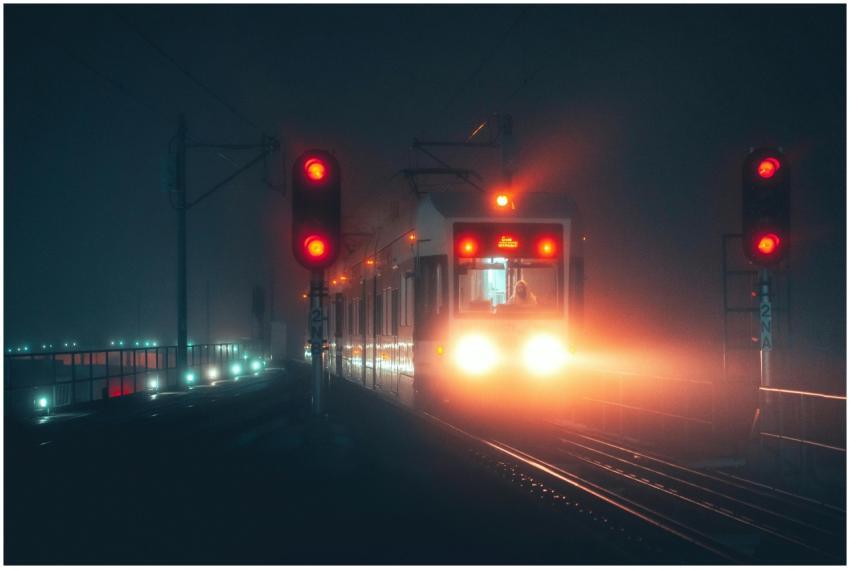 A tram moving through fog at night with glowing si
