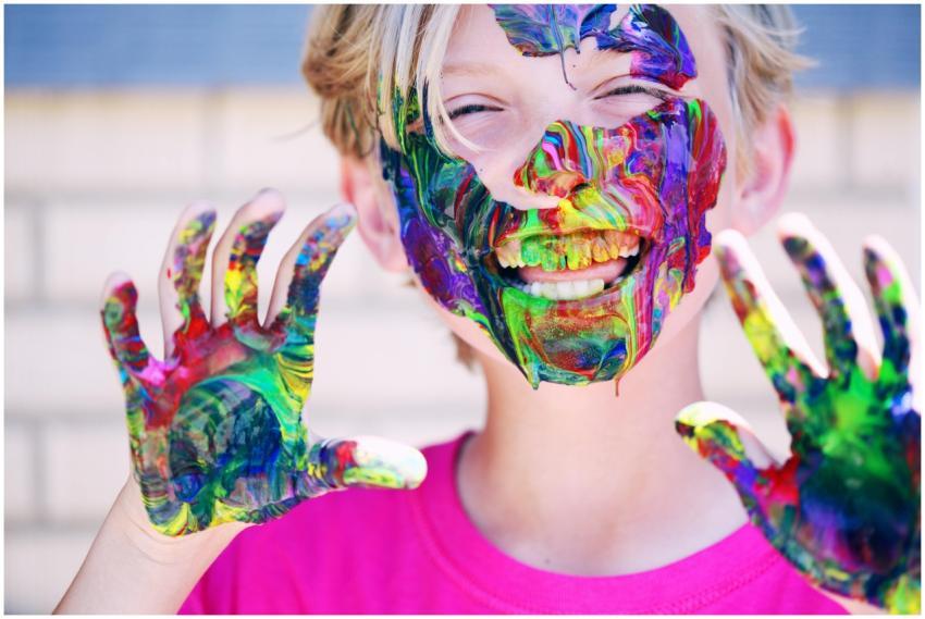 A joyful child with vibrant face paint and hands,