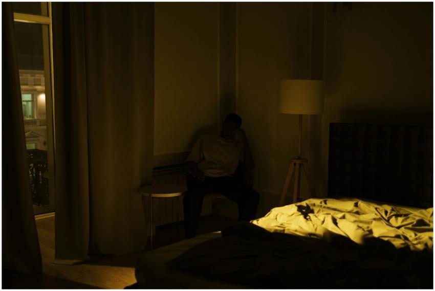 An adult man experiencing insomnia, sitting in a d