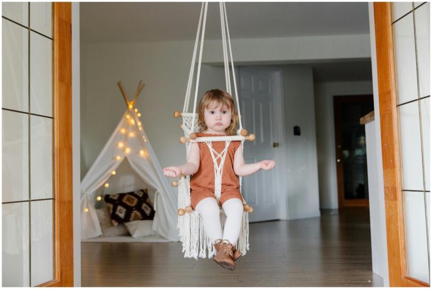 Adorable child sitting relaxed on a swing indoors,