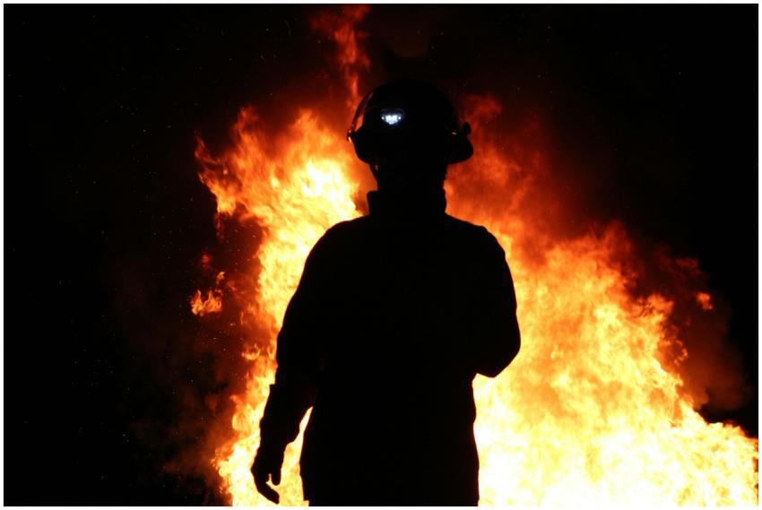 A silhouetted firefighter stands against a backdro