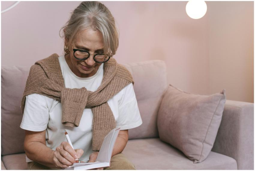 Senior woman with glasses writing in a notebook wh