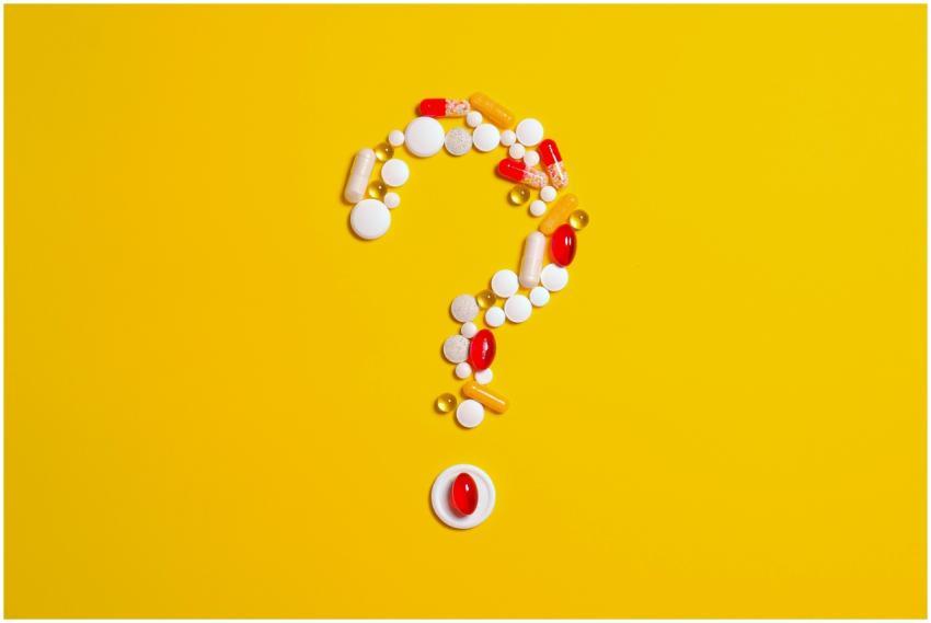 Assorted pills and capsules arranged in a question