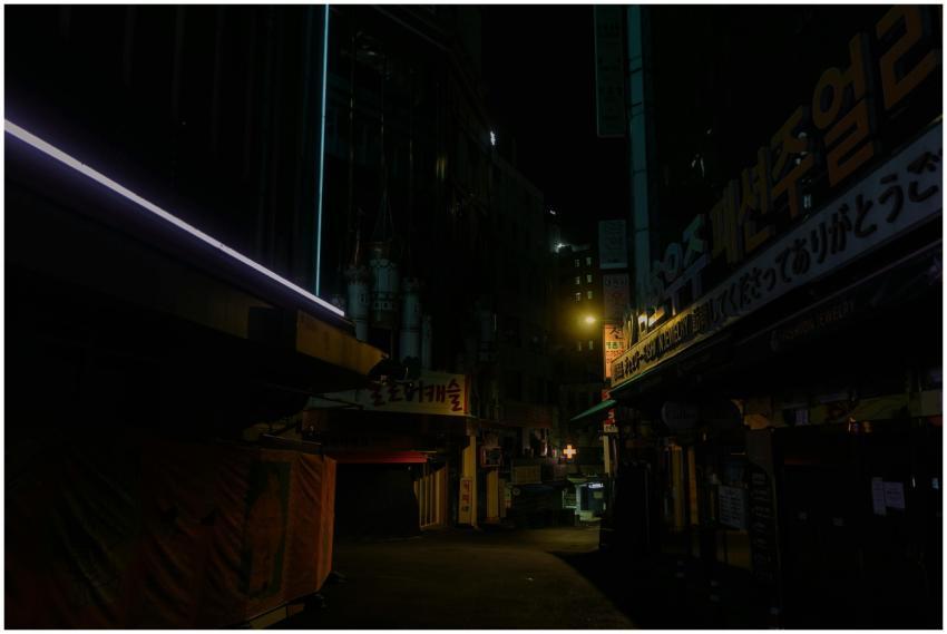 A dimly lit urban alley at night with neon signs a