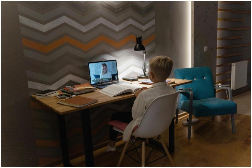 Young boy attending virtual class at home desk wit