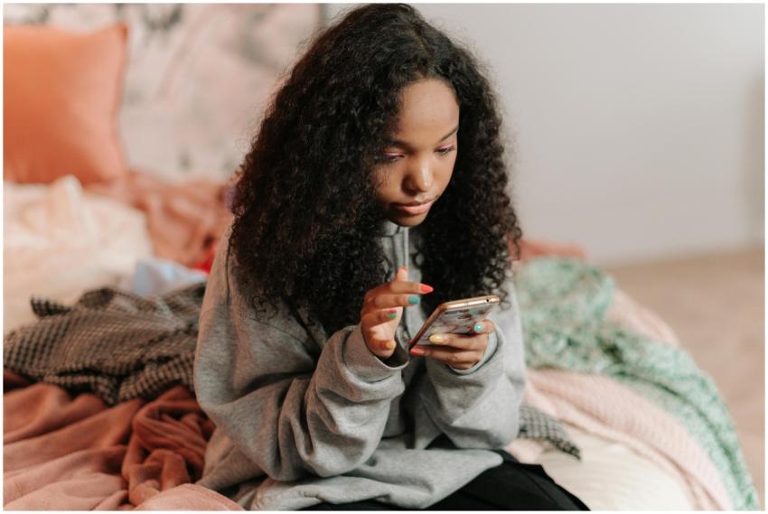 A teenage girl with curly hair using a smartphone