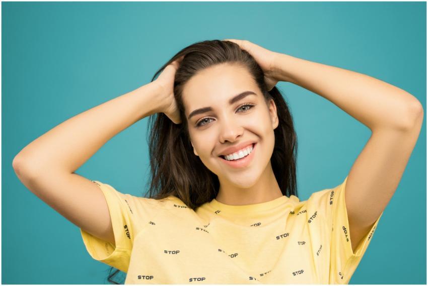 A cheerful woman in a yellow shirt poses against a