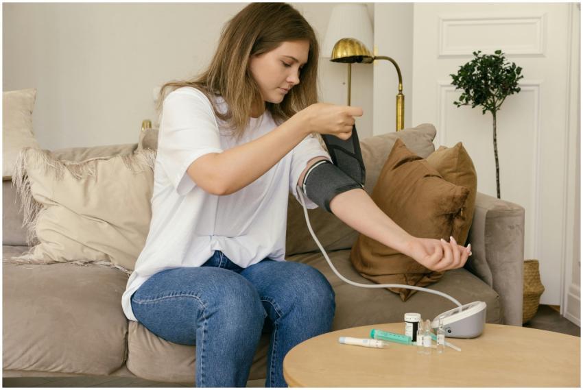 A woman uses a digital blood pressure monitor sitt