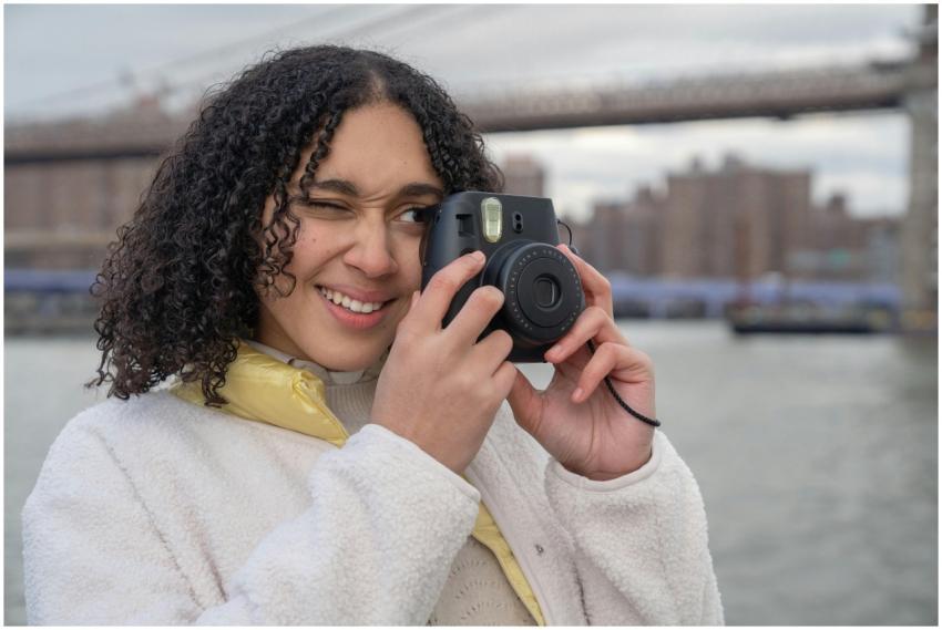 Young woman taking photos near a city bridge with