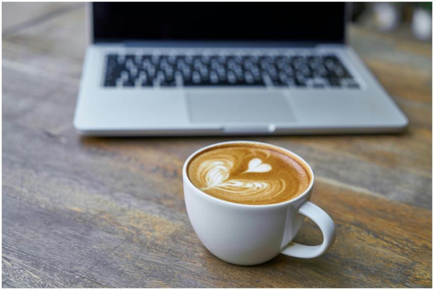 A cappuccino with heart-shaped latte art on a wood