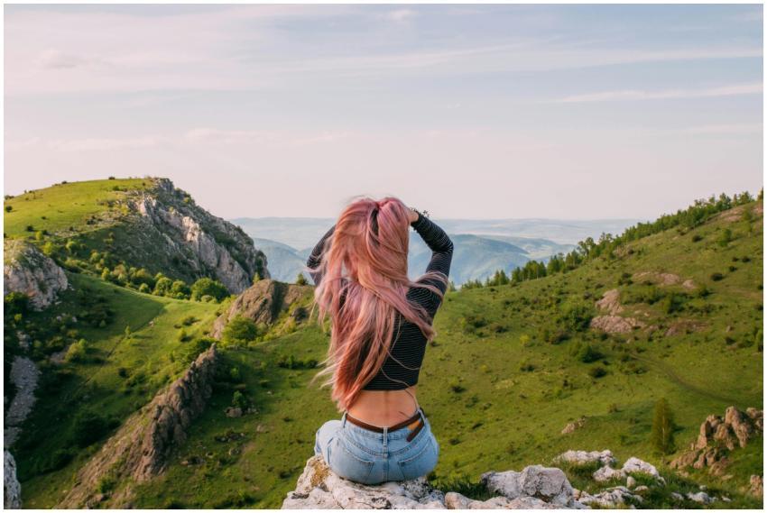 A woman enjoys a scenic view of green mountains an