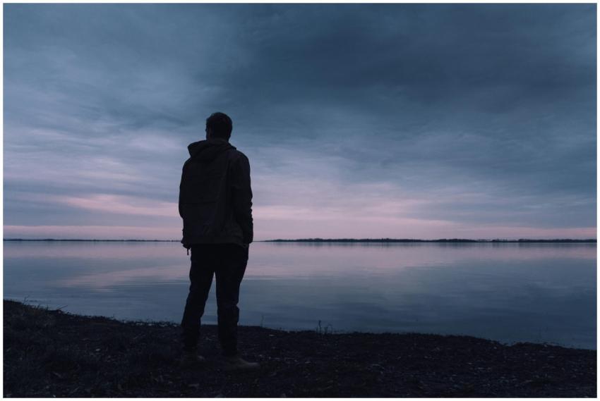 A solitary silhouette of a man in a jacket gazing