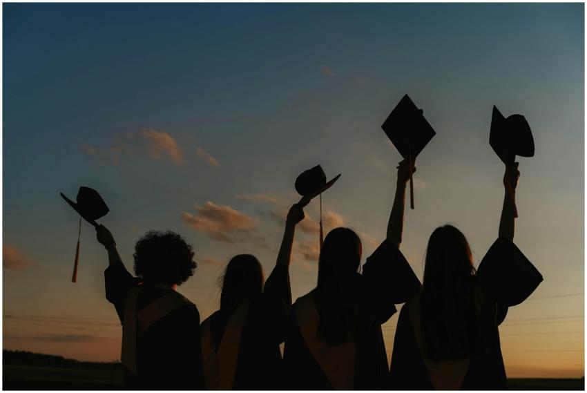 Silhouette of graduates raising caps in joy at sun