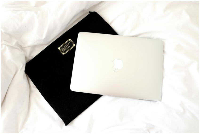 MacBook laptop resting on a bed with a black case,
