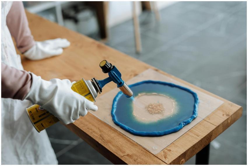 Close-up of hands using blowtorch in resin art on