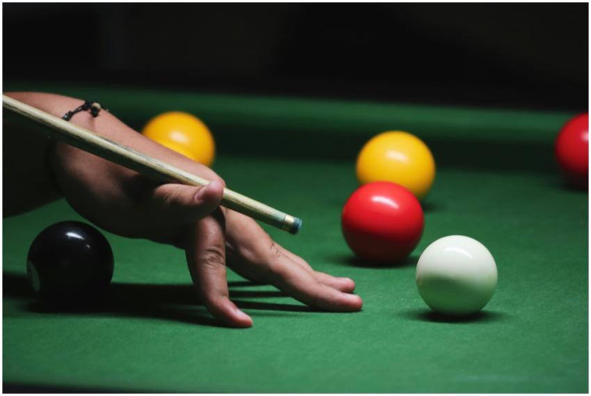 A close-up shot of a hand with a cue stick playing
