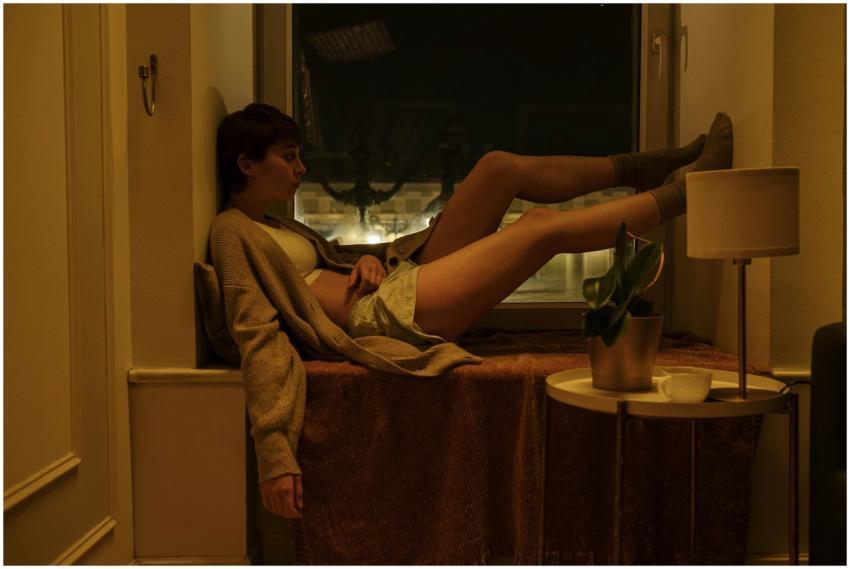 A woman sits by a window at night, exuding a vibe