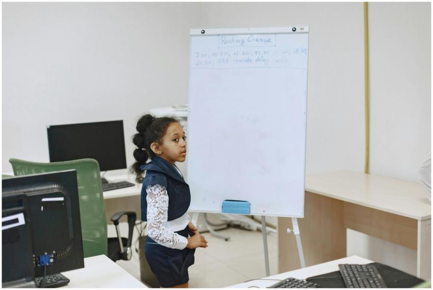 A young girl presents her work on a whiteboard in
