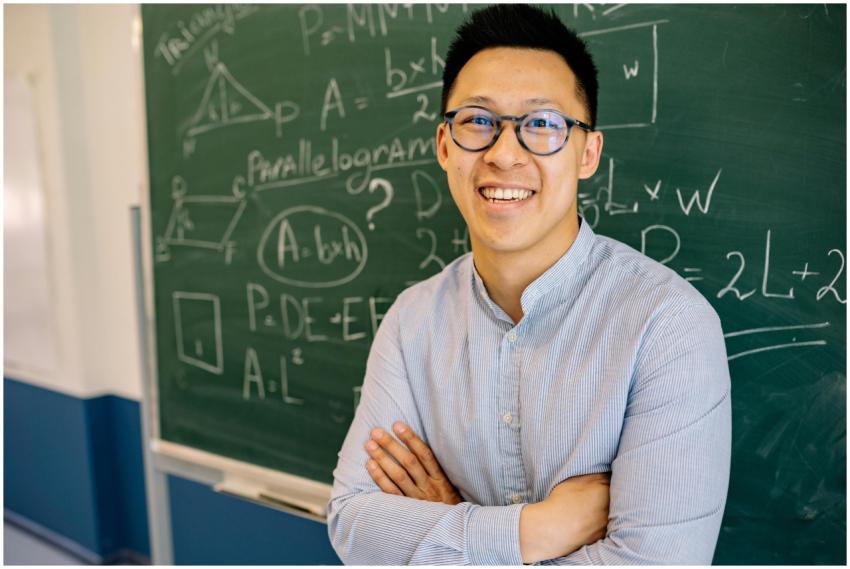 Smiling teacher with glasses stands confidently be