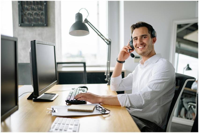 Smiling call center agent working at a desk with a