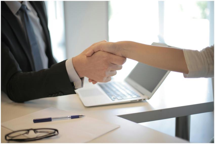 Close-up of a professional handshake over a laptop