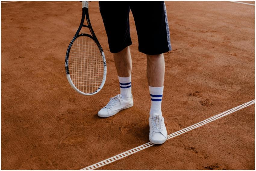 Man standing on a clay tennis court holding a rack
