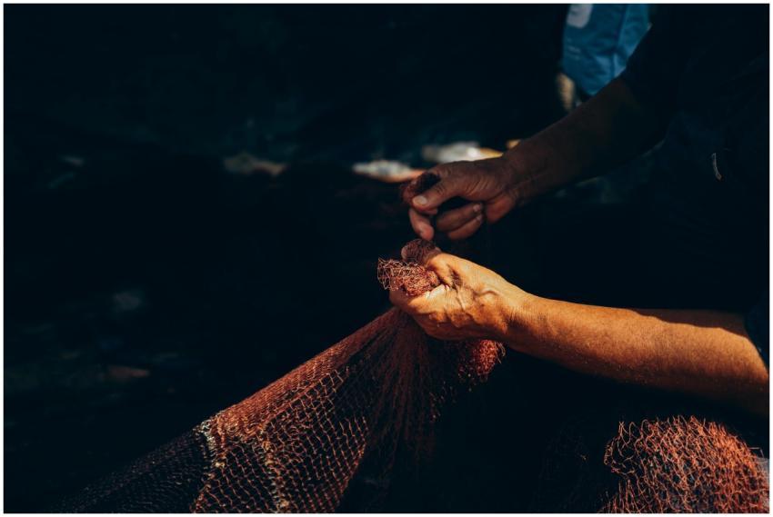 A close-up of hands repairing a fishing net in Dam