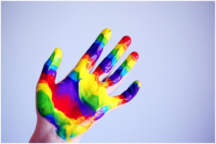A vibrant hand covered in rainbow paint against a