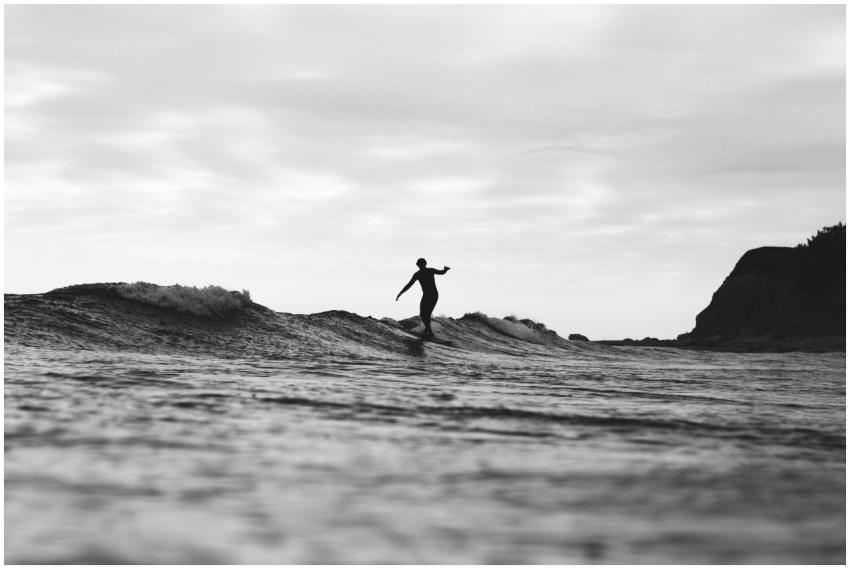 A black and white silhouette of a surfer gliding o