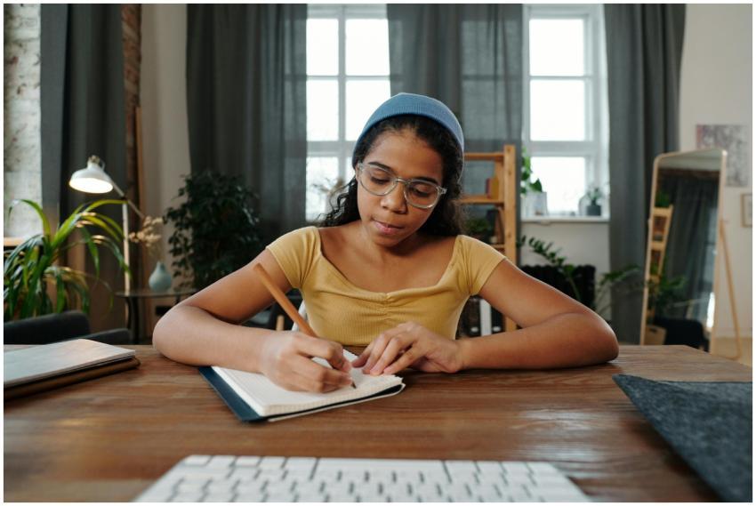 Teen girl focused on writing notes in a notebook a
