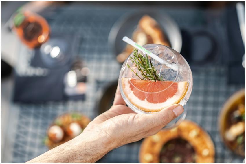 A hand holding a refreshing grapefruit cocktail wi