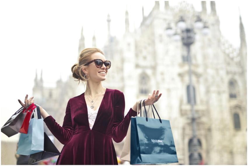 Stylish woman in sunglasses enjoys shopping in fro