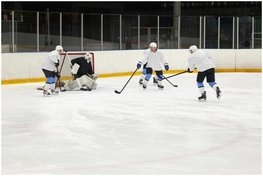 Four ice hockey players compete fiercely on an ind