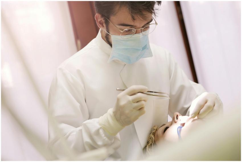 A dentist wearing a mask and gloves treating a pat