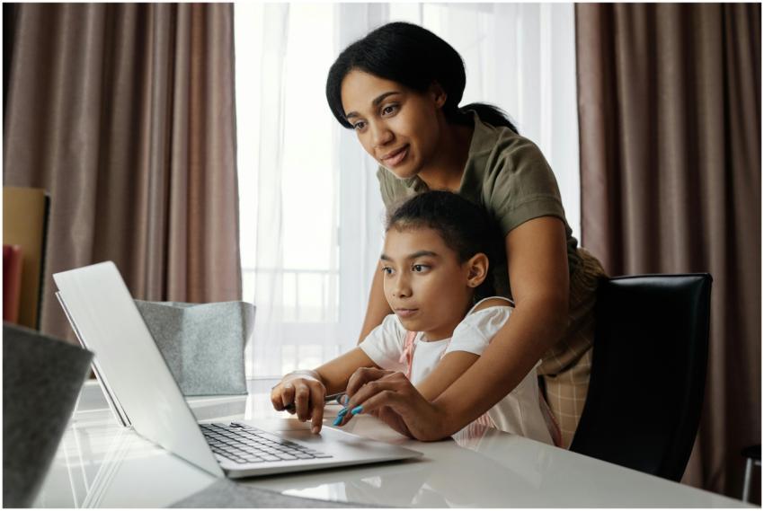 A mother helps her daughter with an online lesson