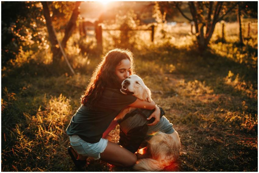 A woman hugs her Golden Retriever during a warm su
