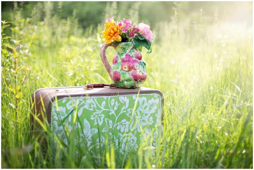 A colorful floral jug on a vintage suitcase in a s