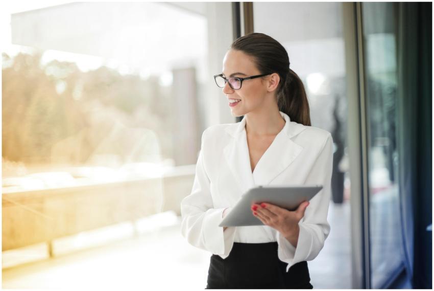 A professional woman in glasses holding a tablet i
