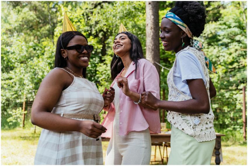 Three women enjoying an outdoor party, wearing hat