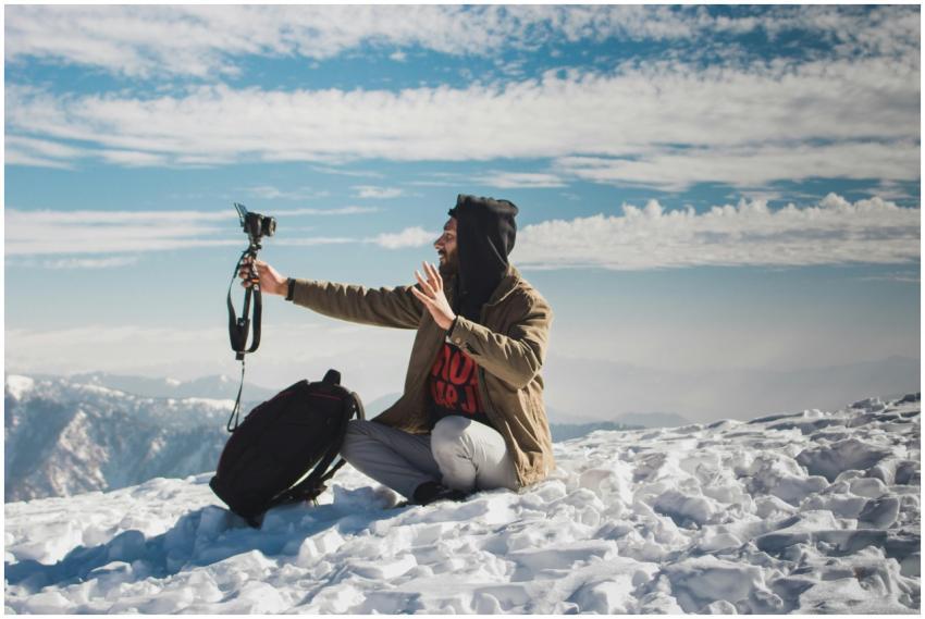 A vlogger captures content amidst the snowy peaks