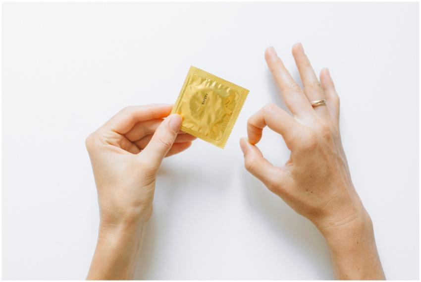 Golden condom packet held by hand, emphasizing saf