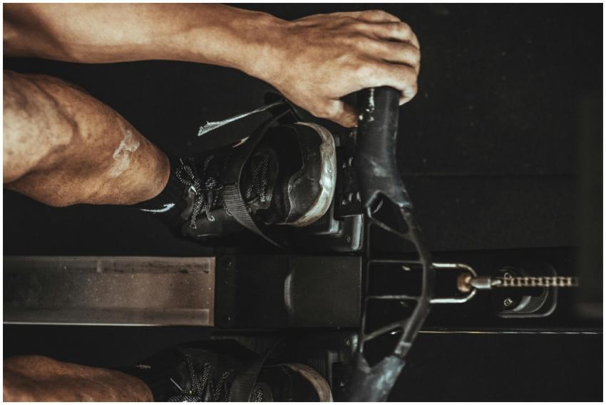 A close-up shot of a man using a rowing machine in