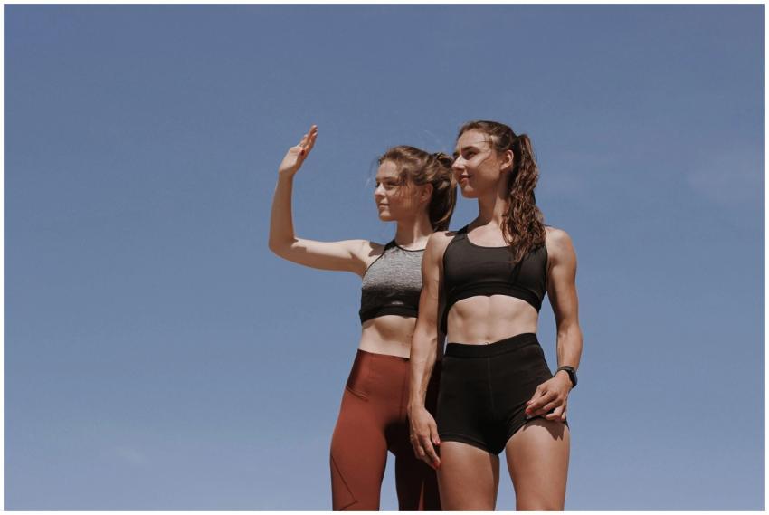 Two fit young women in workout attire posing confi