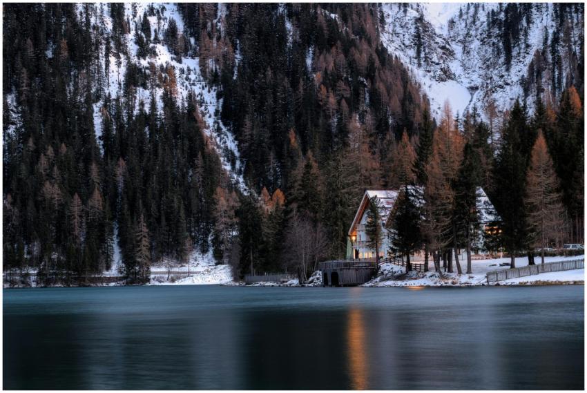 A picturesque chalet by a snow-covered lake surrou